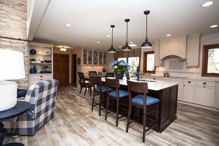 A kitchen with a large island and stools in a living room.