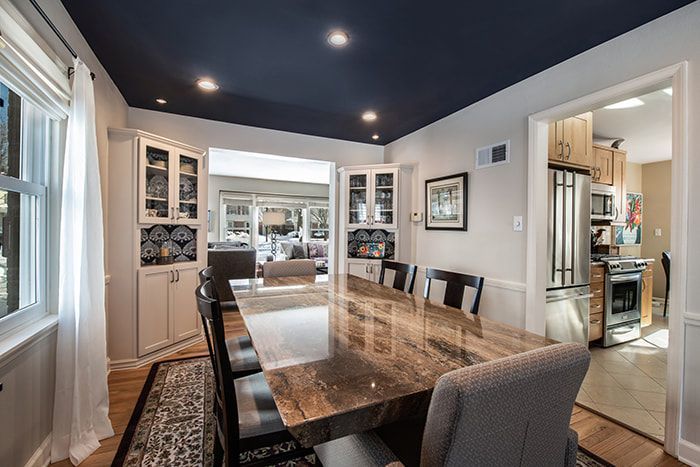 A dining room with a long table and chairs and a blue ceiling.