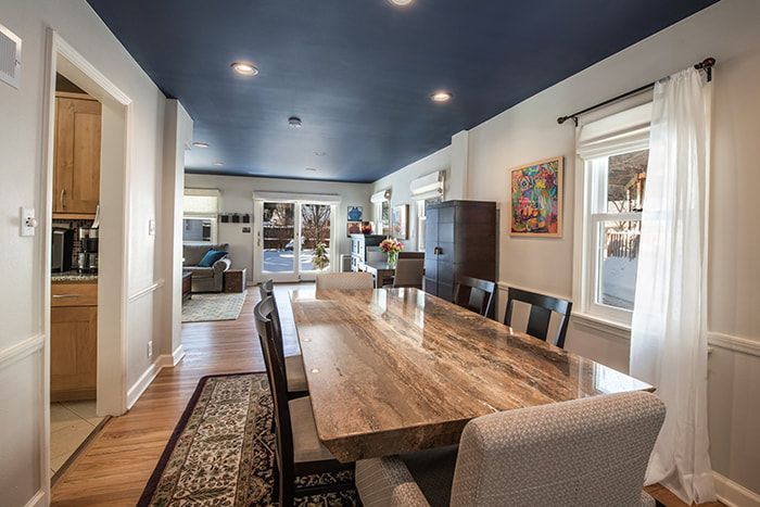A dining room with a long table and chairs and a blue ceiling.