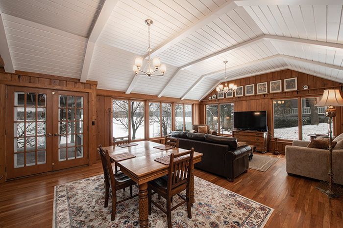 A living room with a dining table , chairs , a couch and a television.