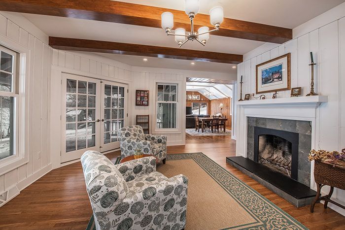 A living room with a fireplace , chairs , and a chandelier.