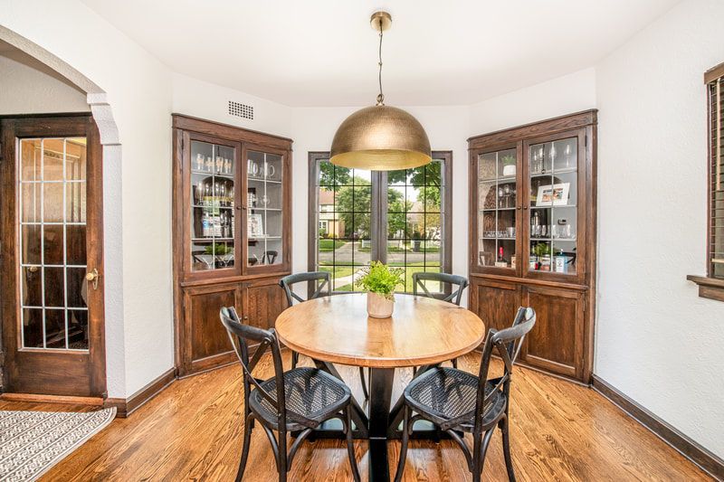 A dining room with a round table and chairs and a pendant light.