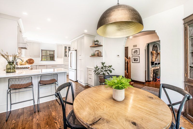 A dining room with a round wooden table and chairs in a kitchen.