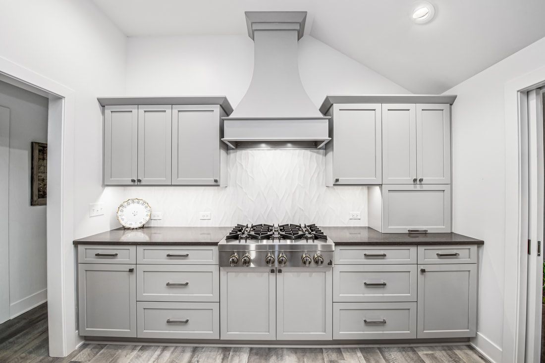 A kitchen with white cabinets and a stove top oven.