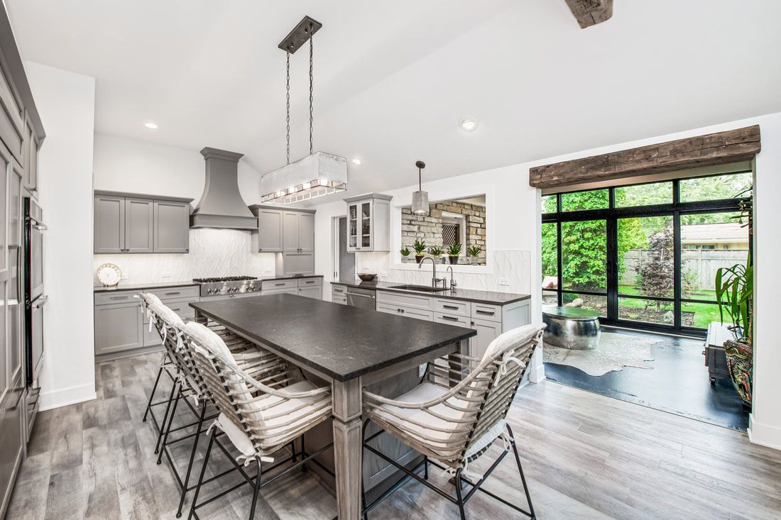 A kitchen with a table and chairs in it and a large window.