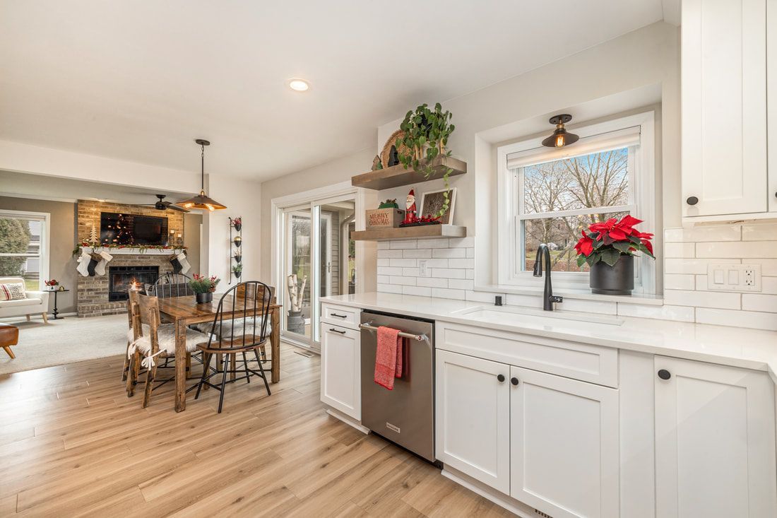 A kitchen with white cabinets , a sink , a dishwasher , and a dining room.