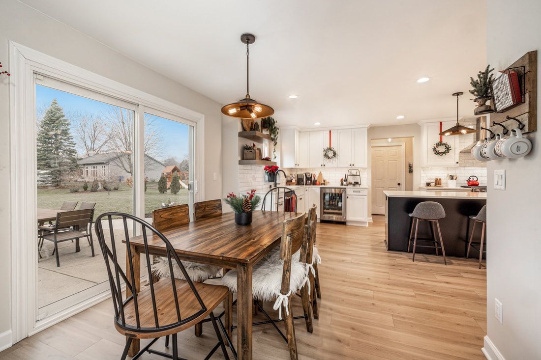 A dining room with a wooden table and chairs and a sliding glass door leading to a kitchen.