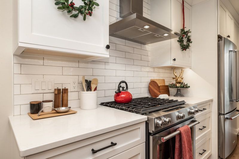 A kitchen with white cabinets , stainless steel appliances , a stove and a refrigerator.