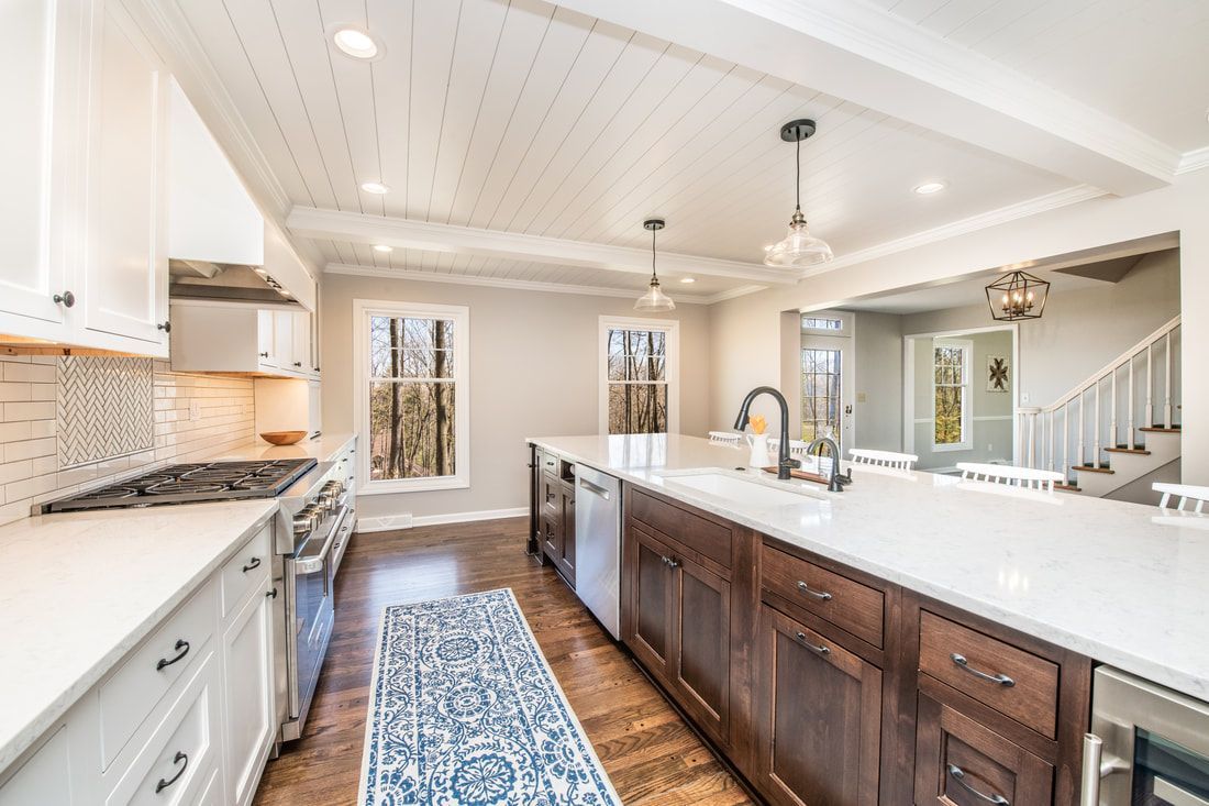 A kitchen with wooden cabinets , white counter tops , stainless steel appliances and a rug.