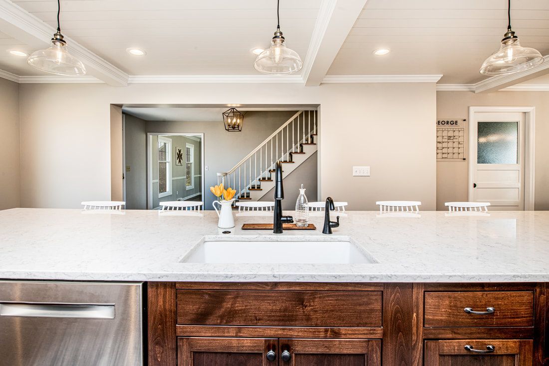A kitchen with a sink , stainless steel dishwasher , and wooden cabinets.