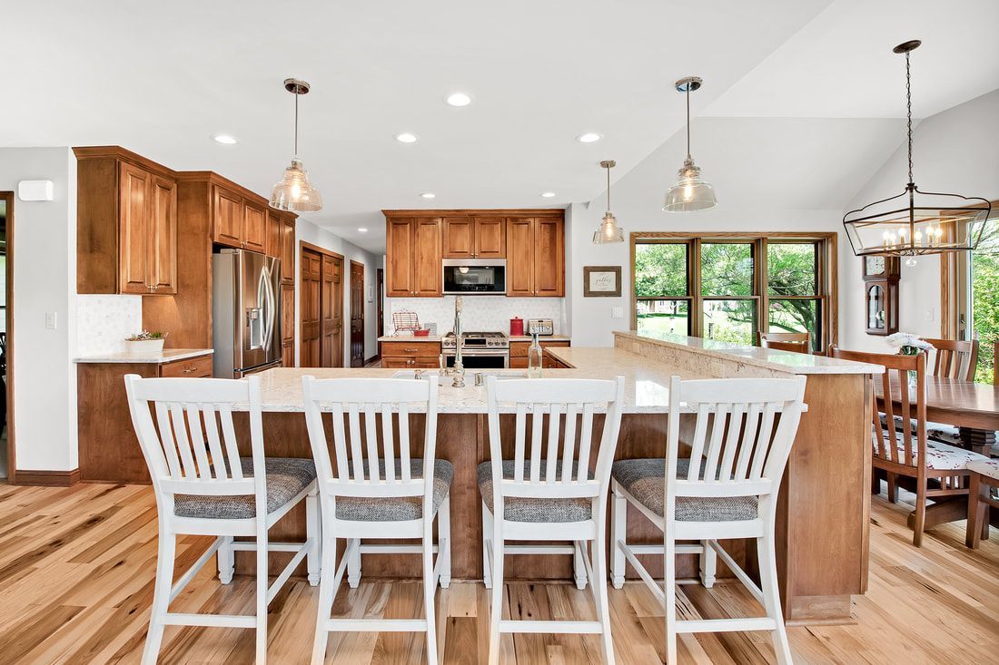 A kitchen with a large island and white chairs.