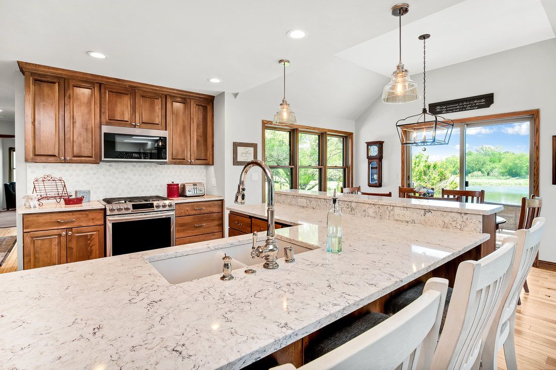 A kitchen with a large island , sink , stove and microwave.