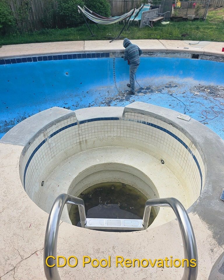 A man is cleaning a swimming pool with a hose.