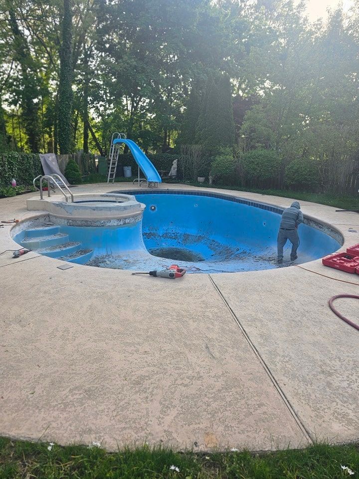 A man is working on a swimming pool in a backyard.