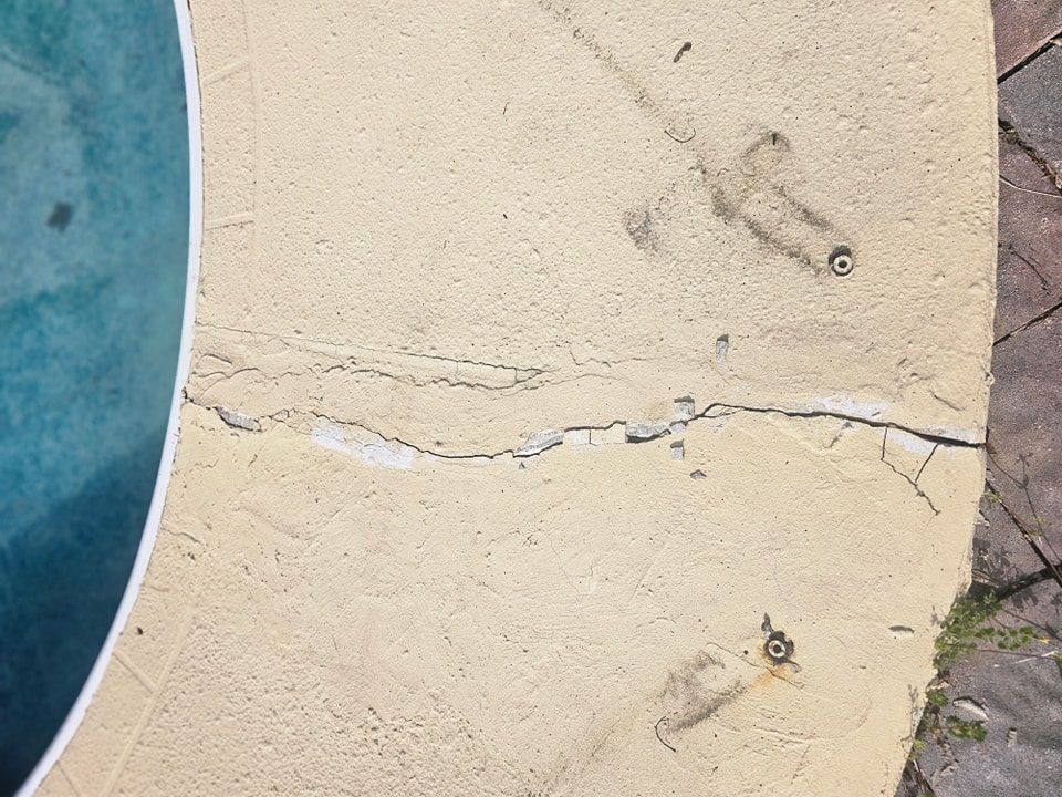 A cracked concrete surface next to a swimming pool