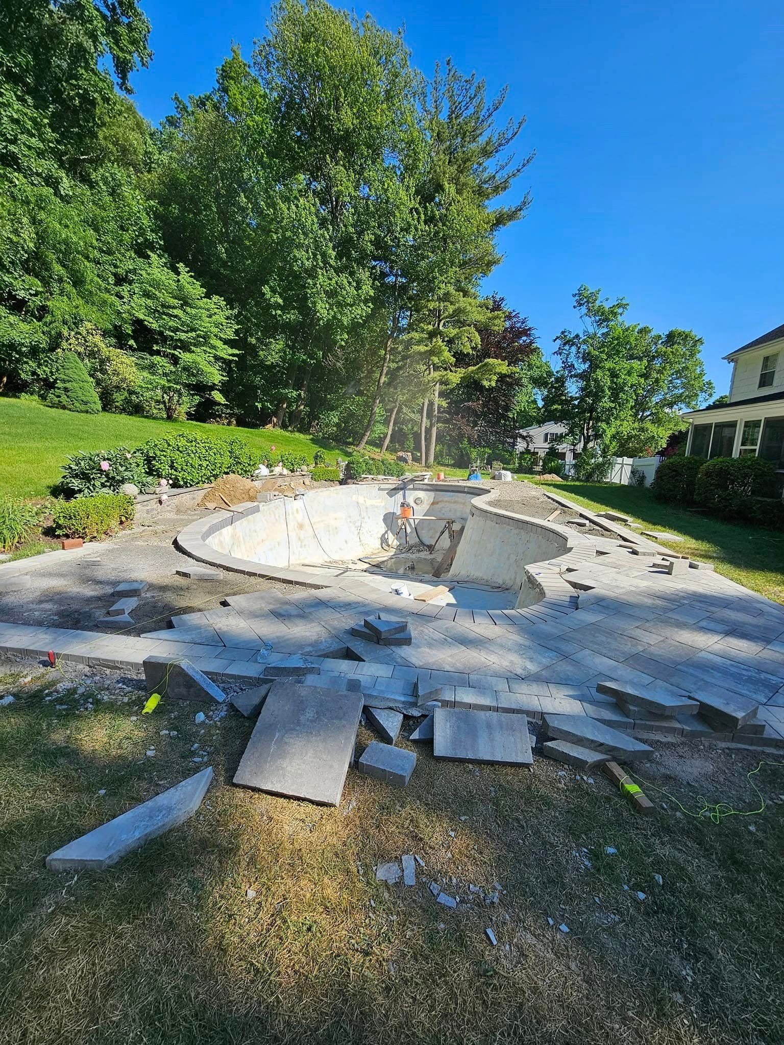 A concrete swimming pool is being demolished in a backyard.