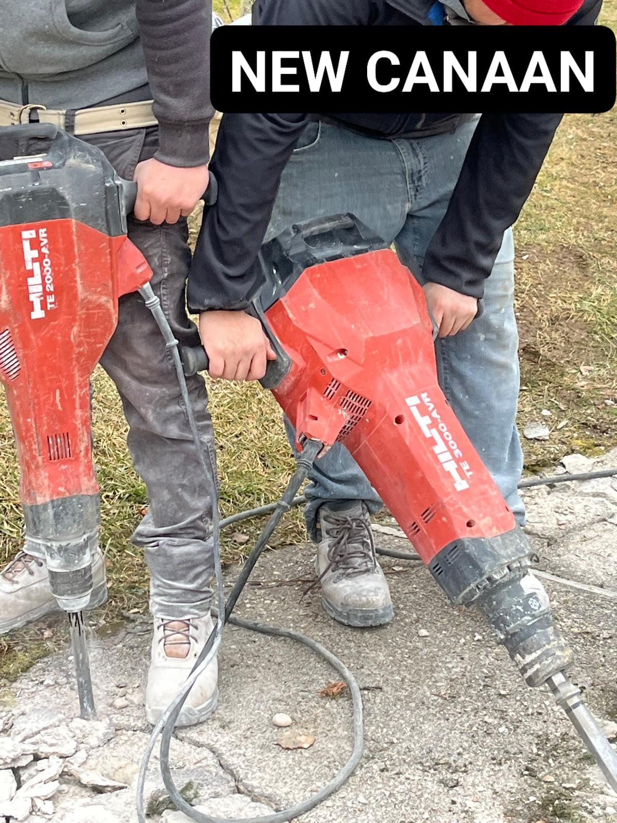 Two men are using a hammer to break concrete.