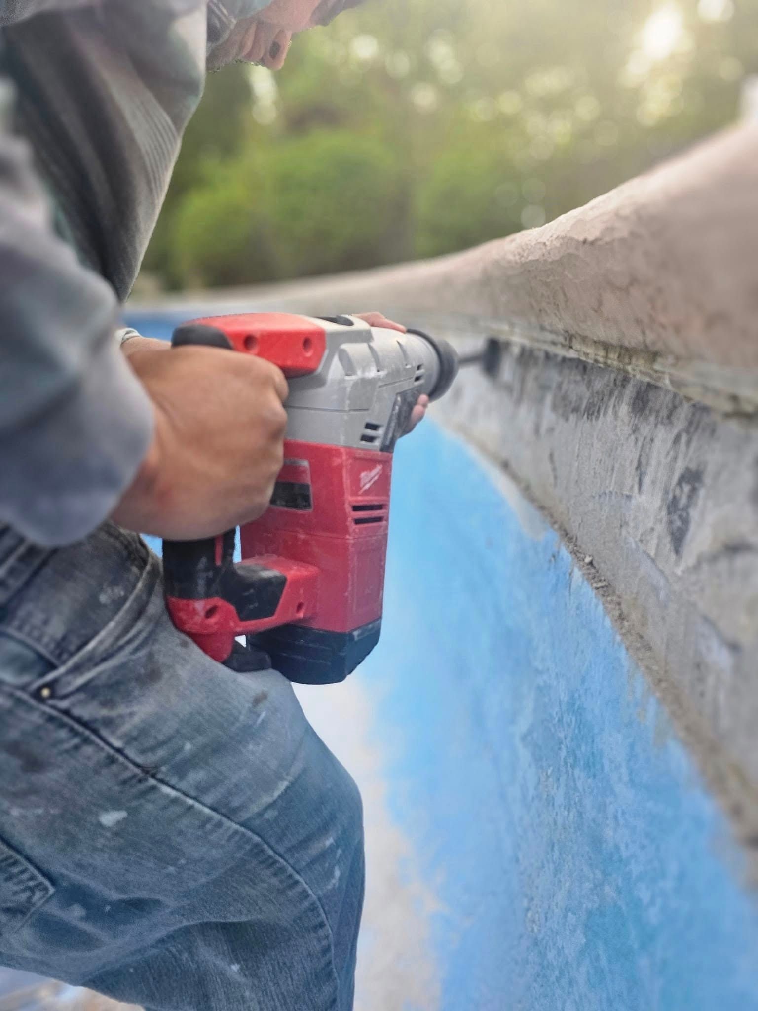 A man is using a hammer drill to drill a hole in a wall.
