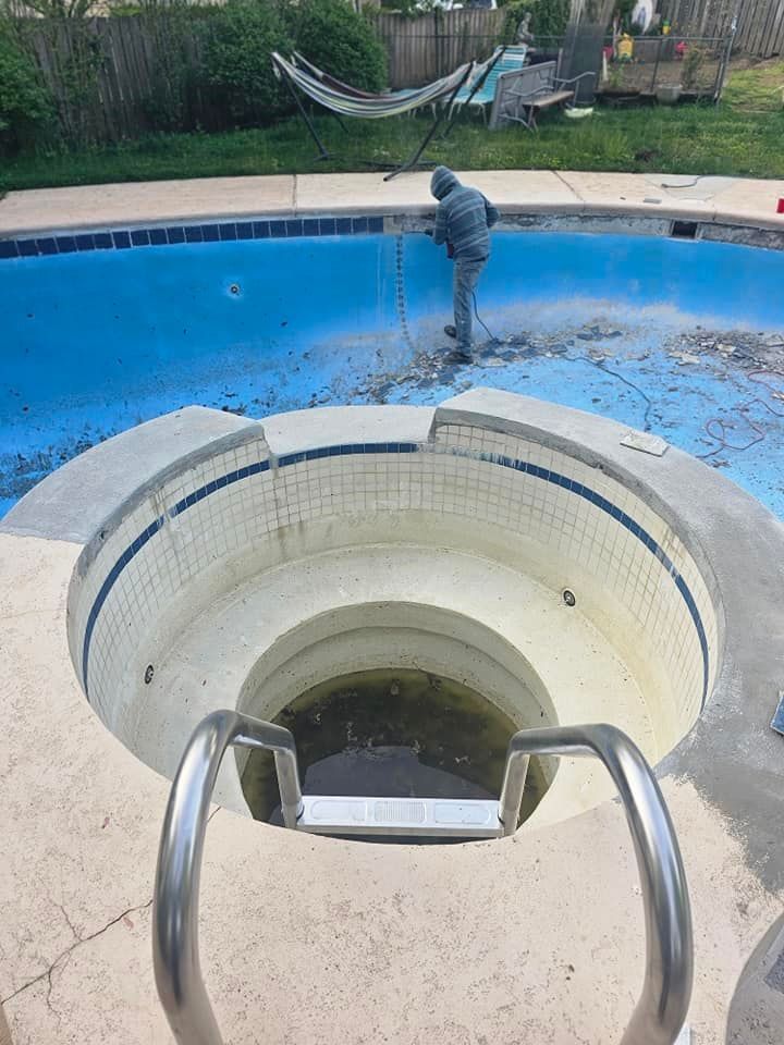 A man is cleaning a swimming pool with a hose.