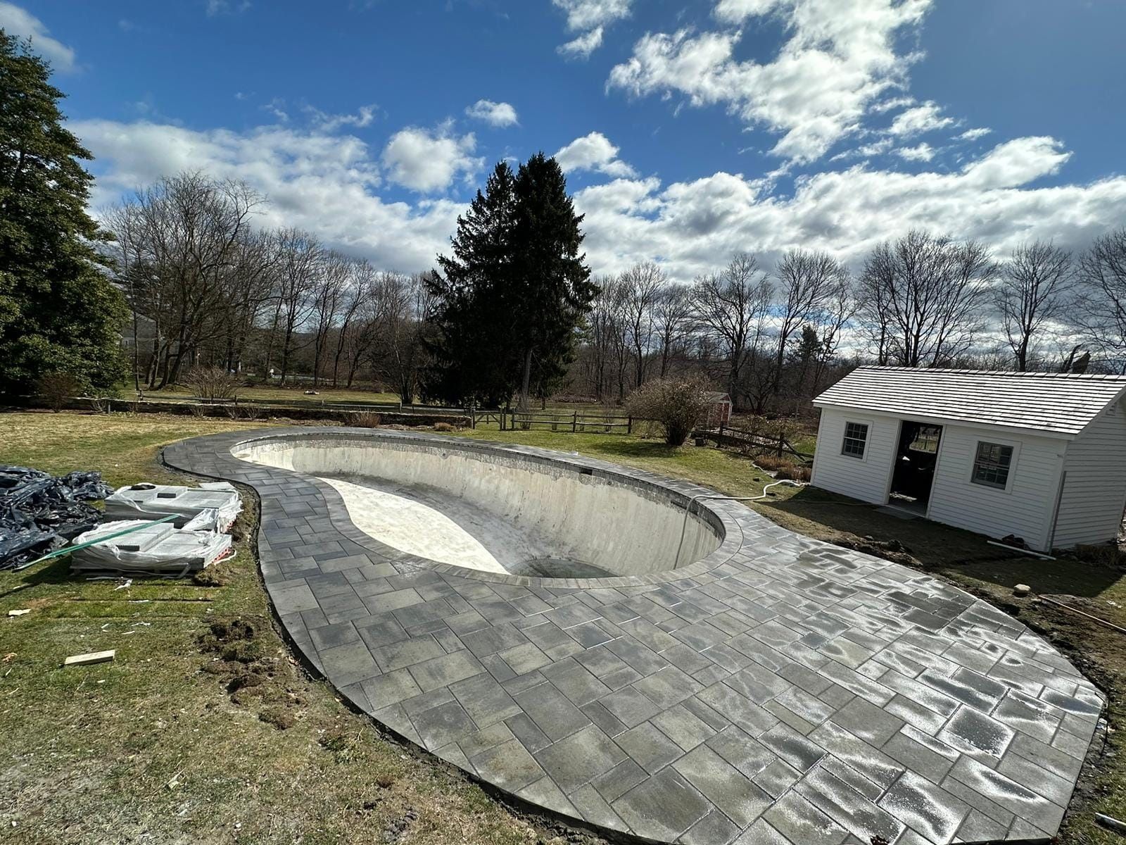 A large swimming pool is being built in the backyard of a house.