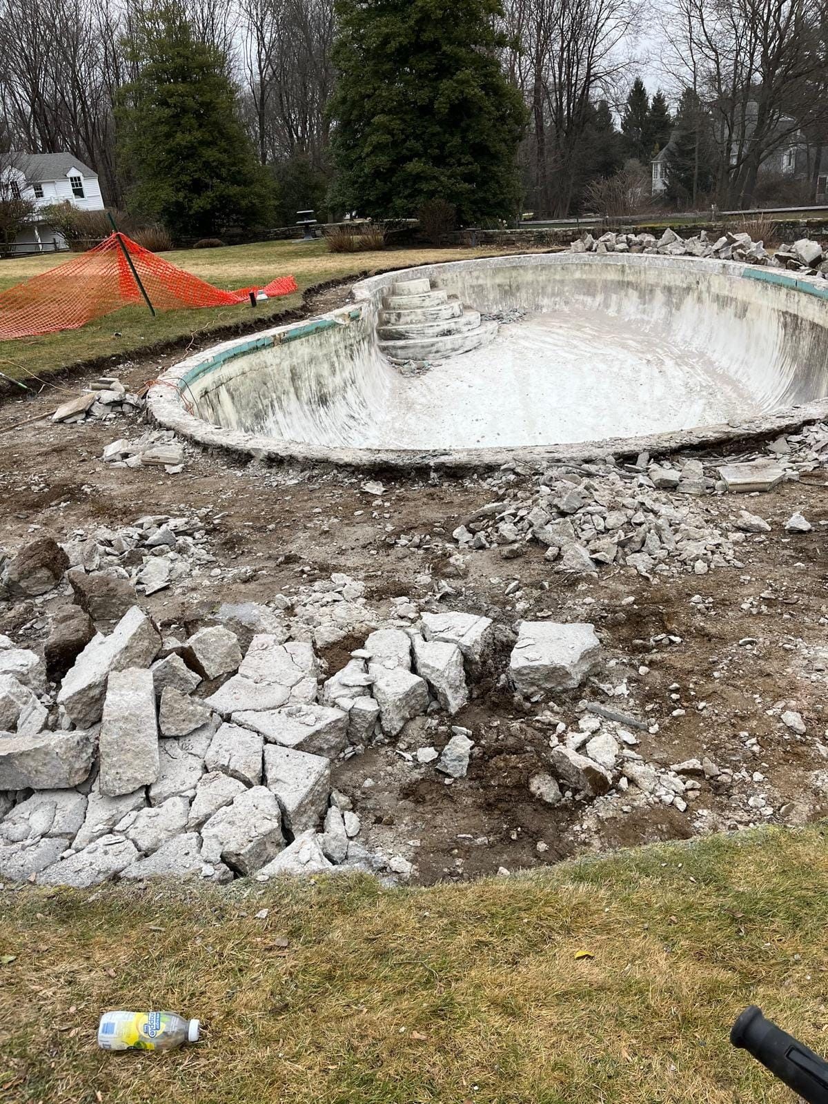 A swimming pool is being demolished in a backyard.