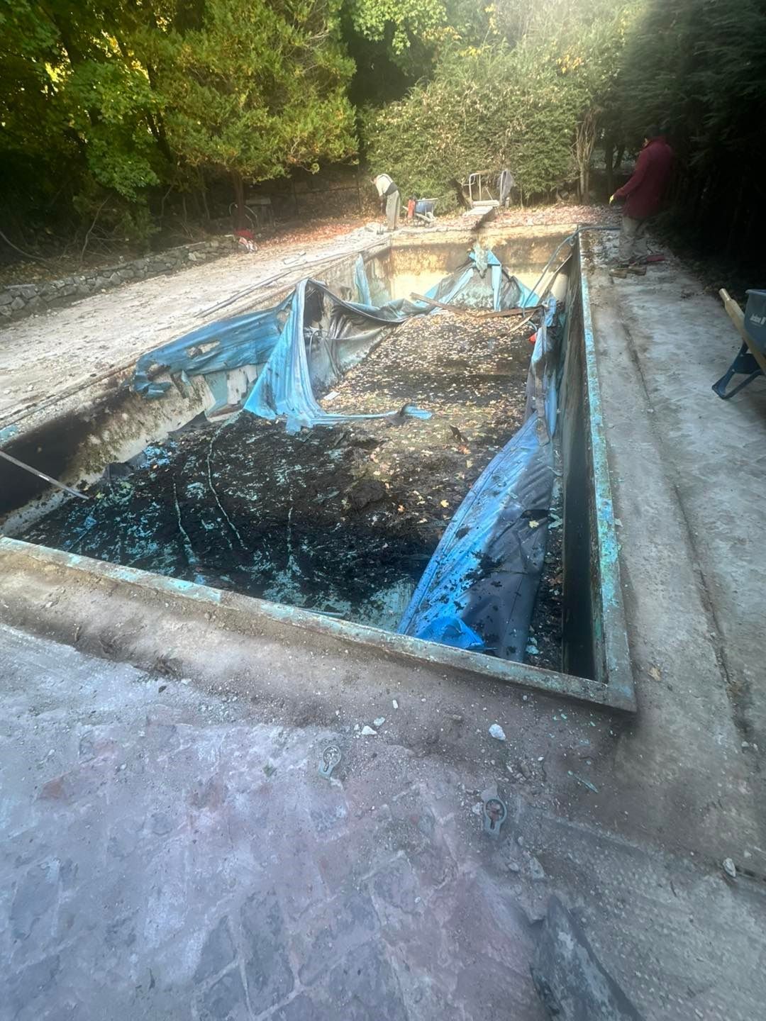 A man is standing next to a swimming pool that is being remodeled.