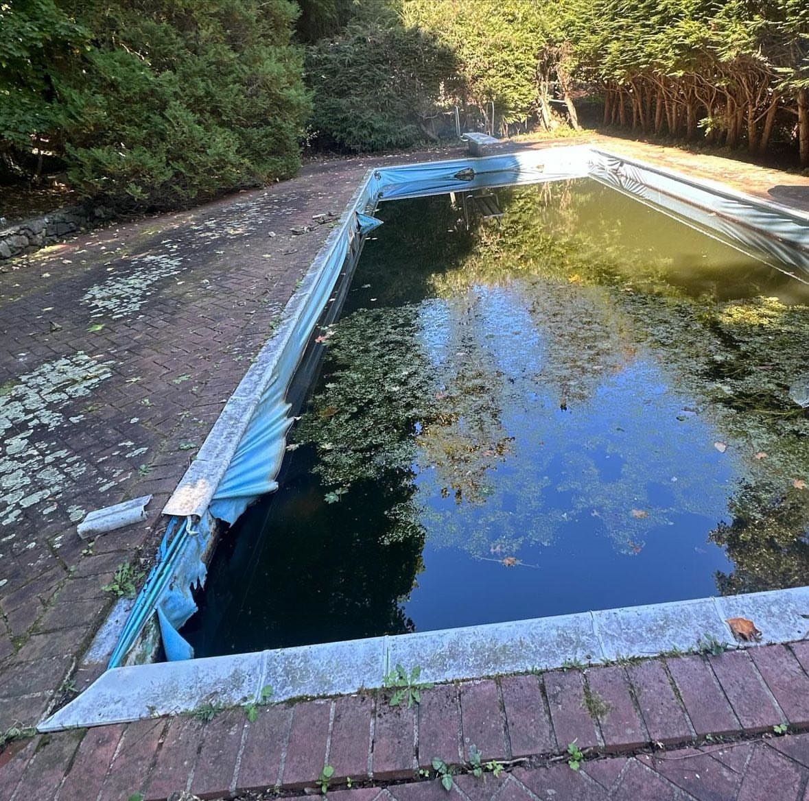 An empty swimming pool with a blue cover on it