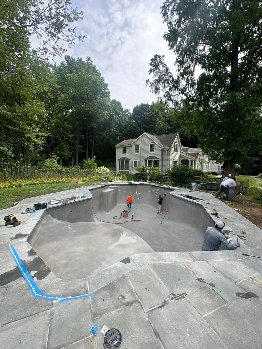 A large swimming pool is being built in the backyard of a house.