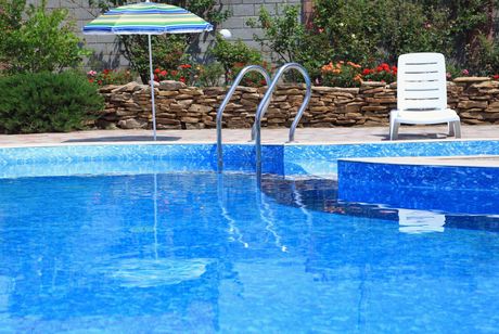 A swimming pool with a chair and umbrella in the background