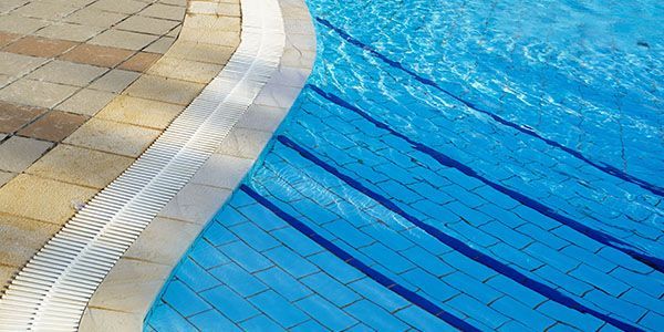 A swimming pool with blue water and a brick border.