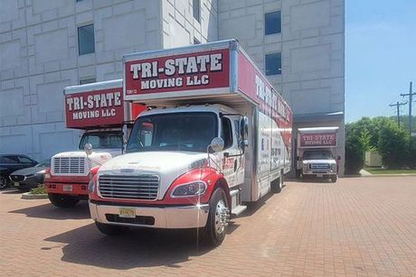 Tri-State Moving LLC trucks parked outside a stone building, including a red-and-white moving van in front.