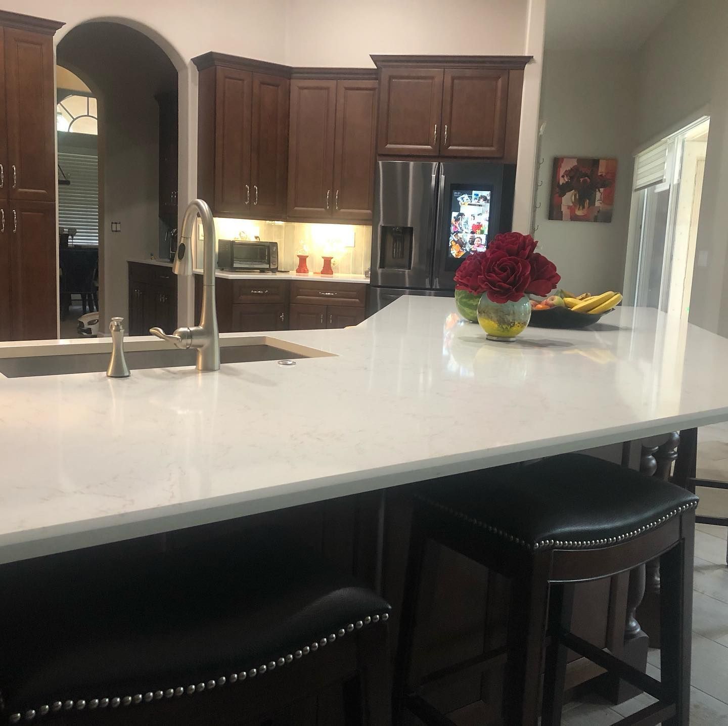 A kitchen with a sink and a stainless steel refrigerator