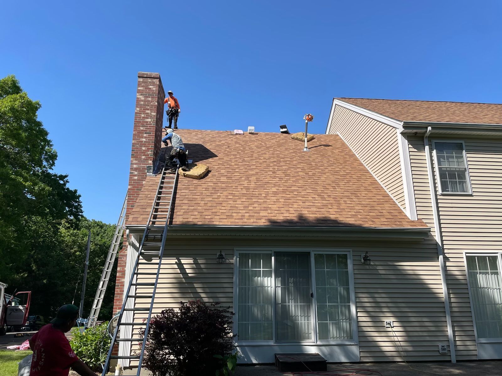 Men are working on the roof of a house using a ladder