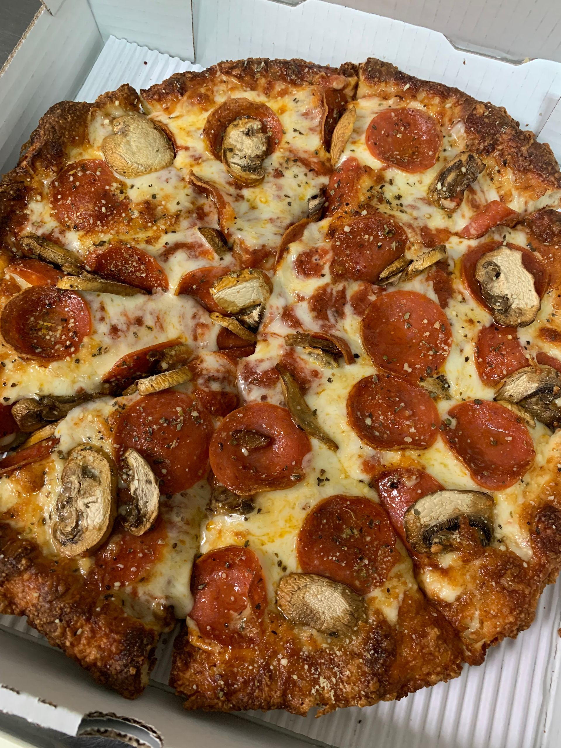A pepperoni pizza with mushrooms and cheese is in a box.