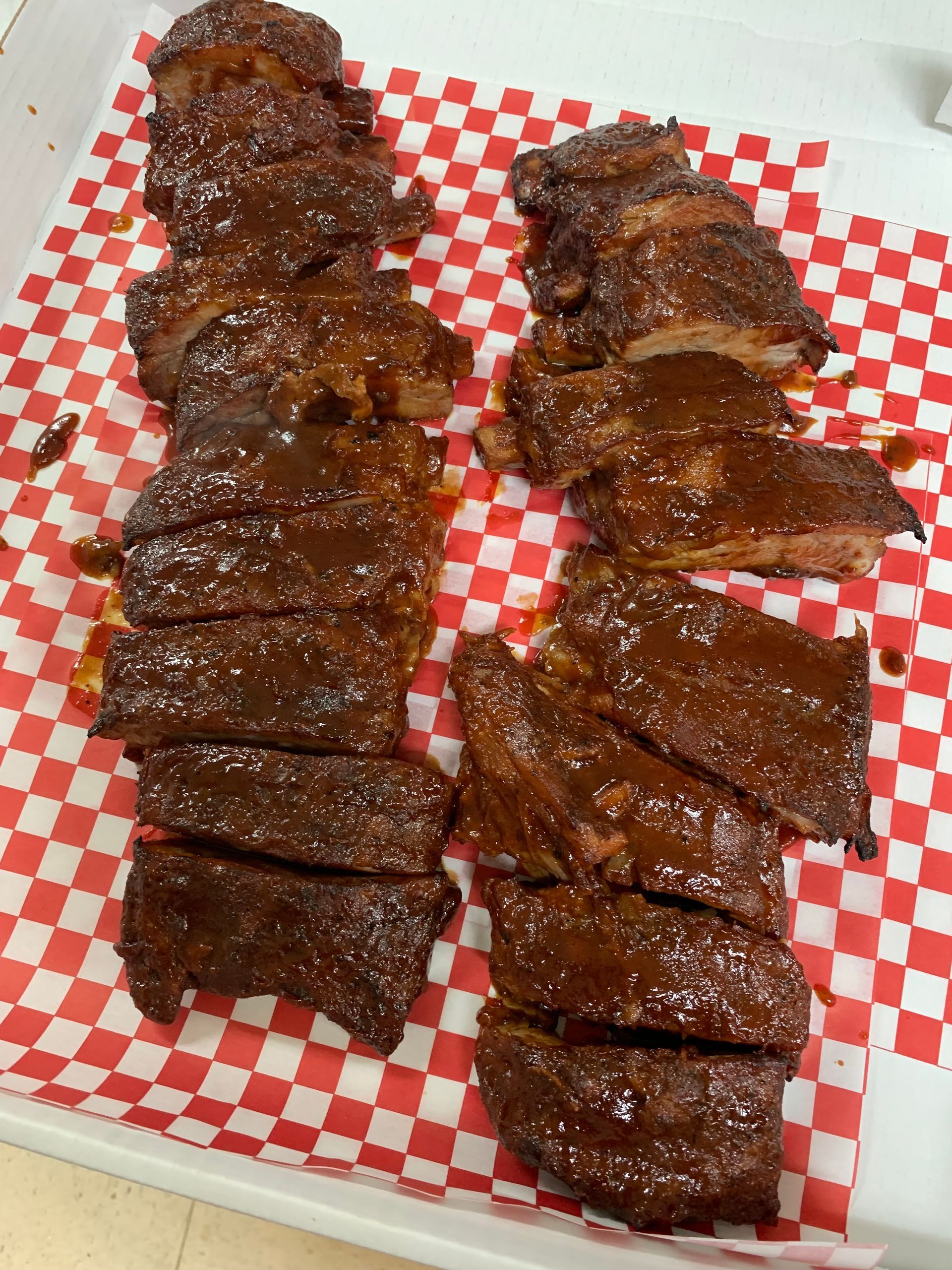 Two ribs are sitting on a checkered paper on a tray.