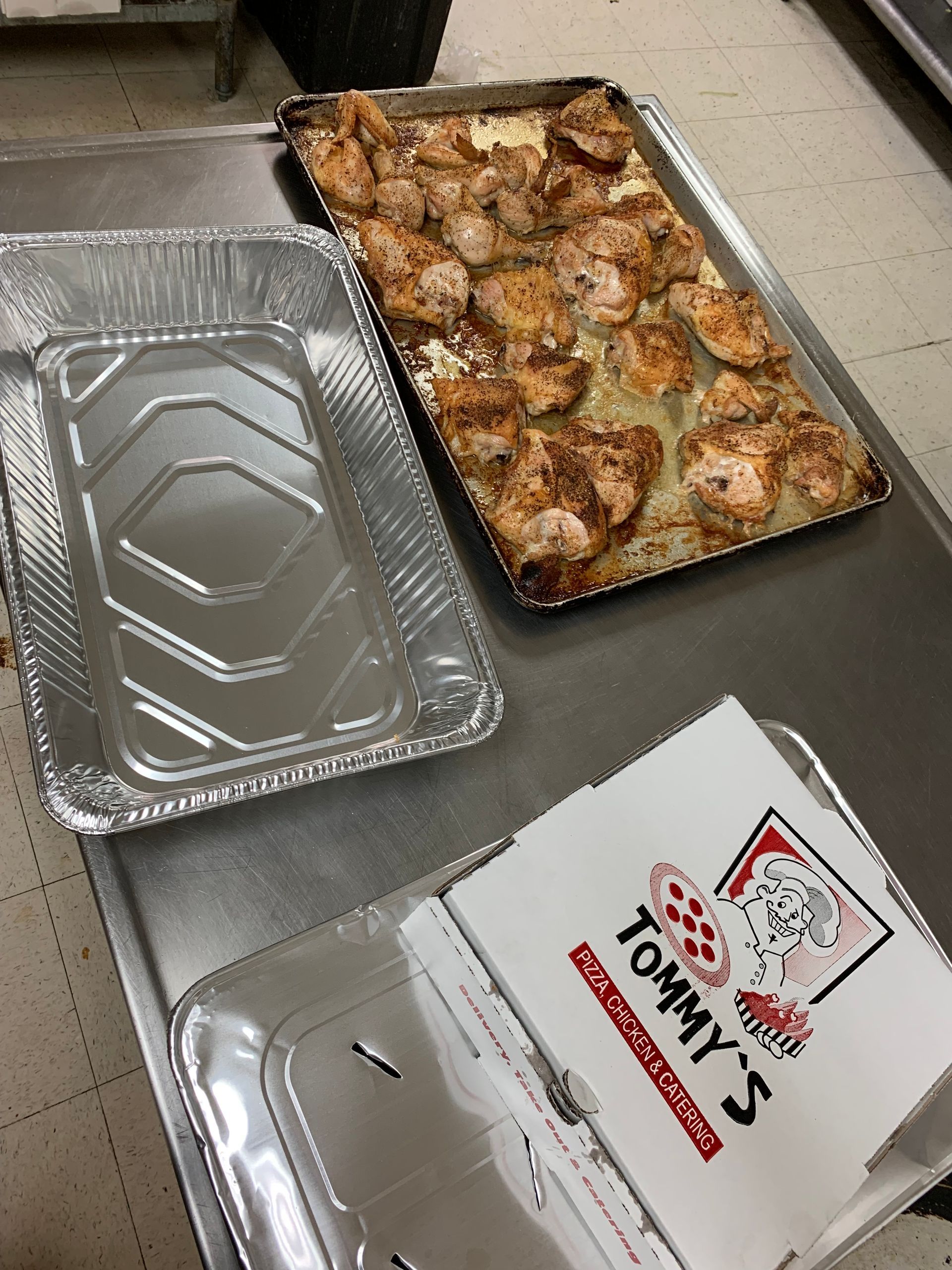 A box of tommy 's pizza sits next to a tray of food