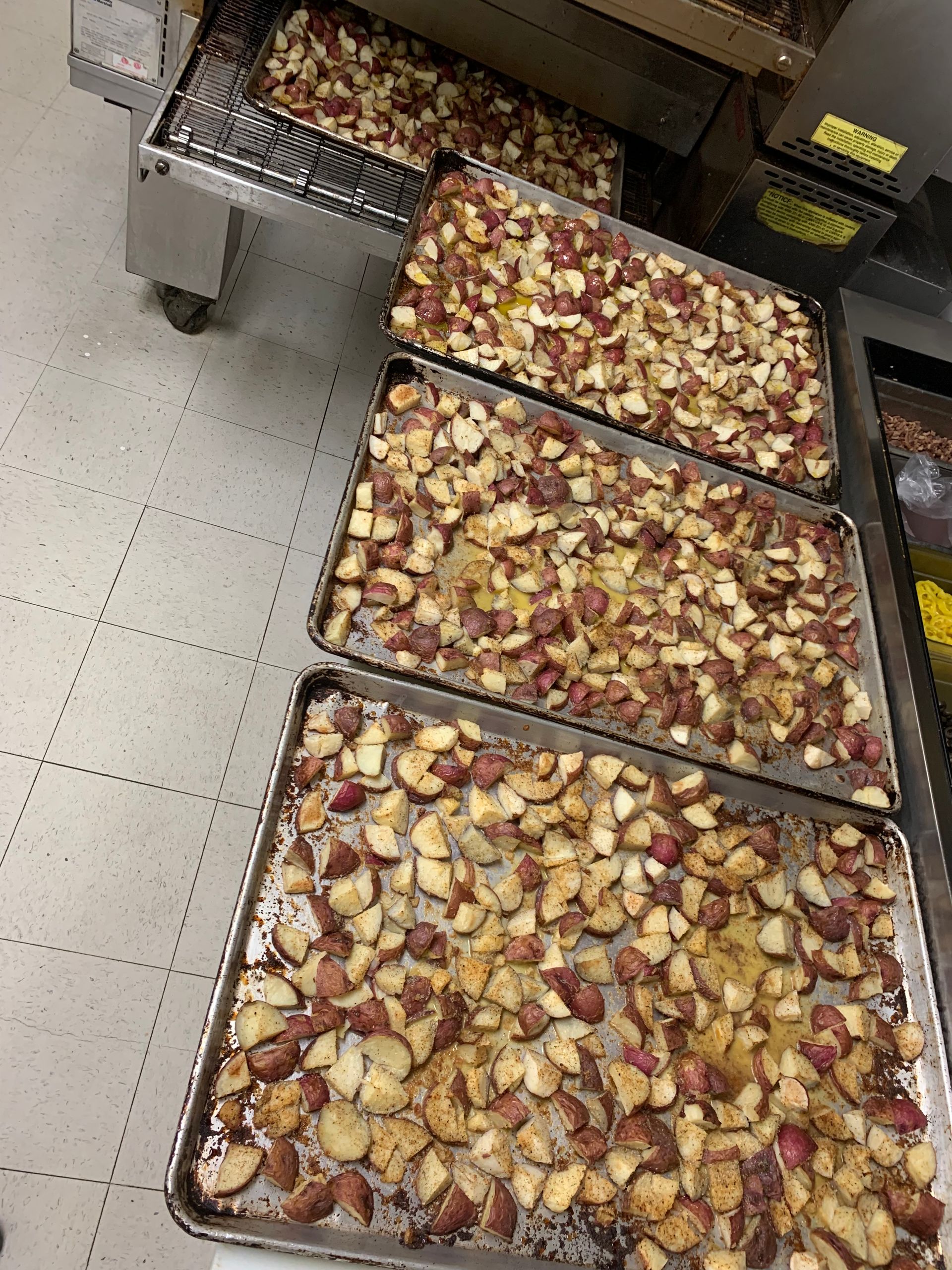 A bunch of trays of food are sitting on the floor in a kitchen.