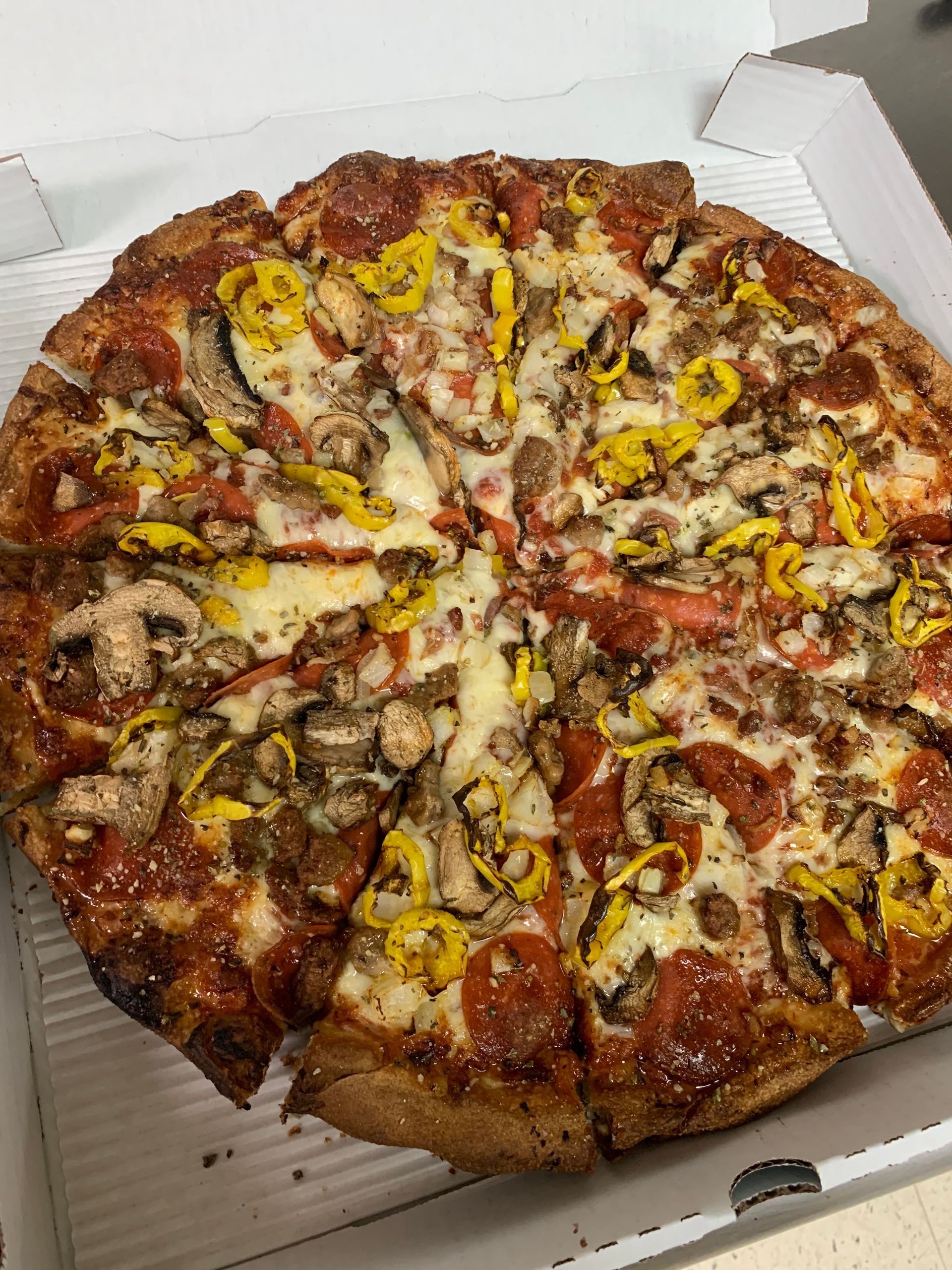 A pizza with pepperoni , mushrooms , and cheese is in a box.