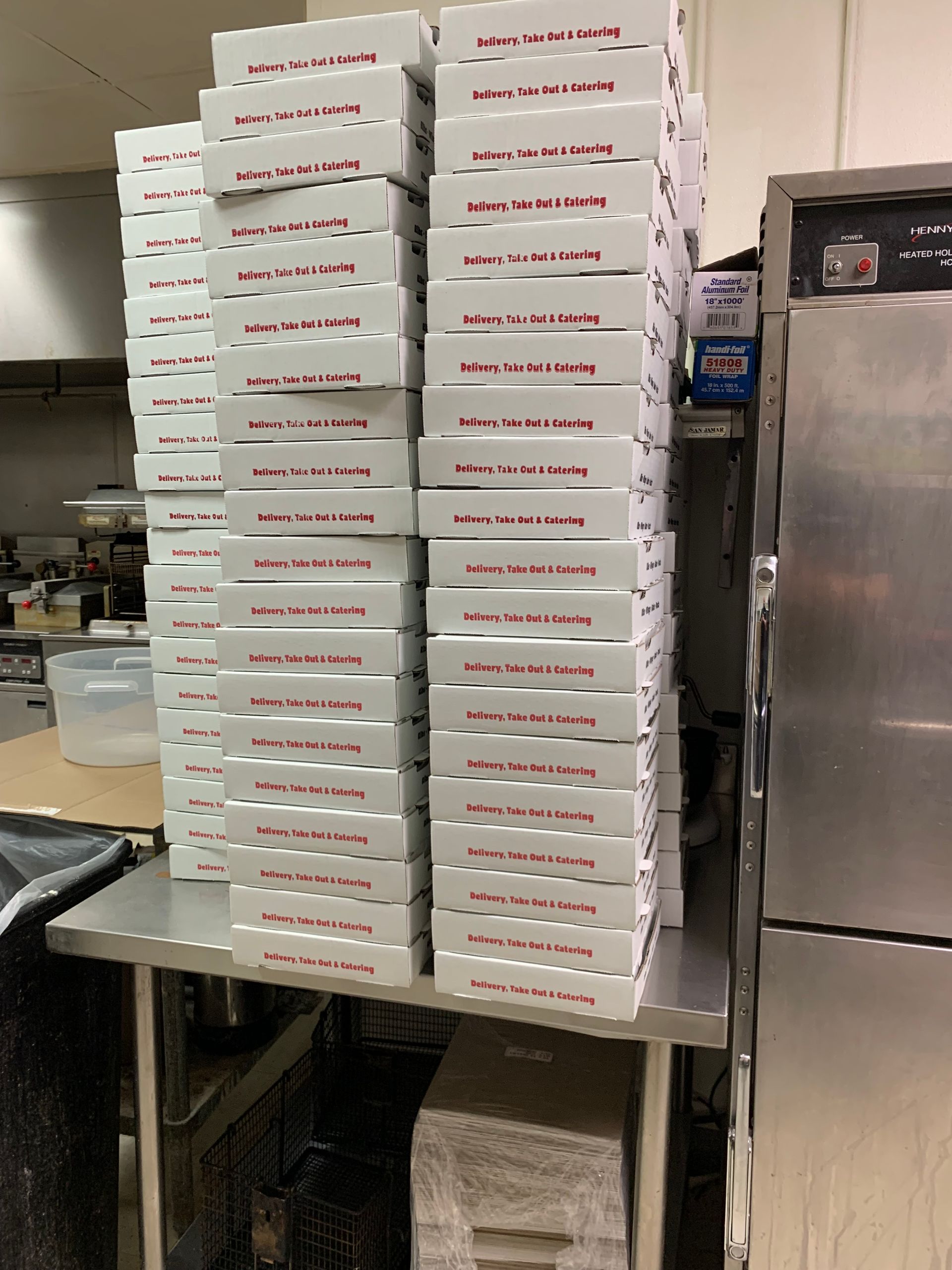 A stack of pizza boxes sitting on top of a metal table.