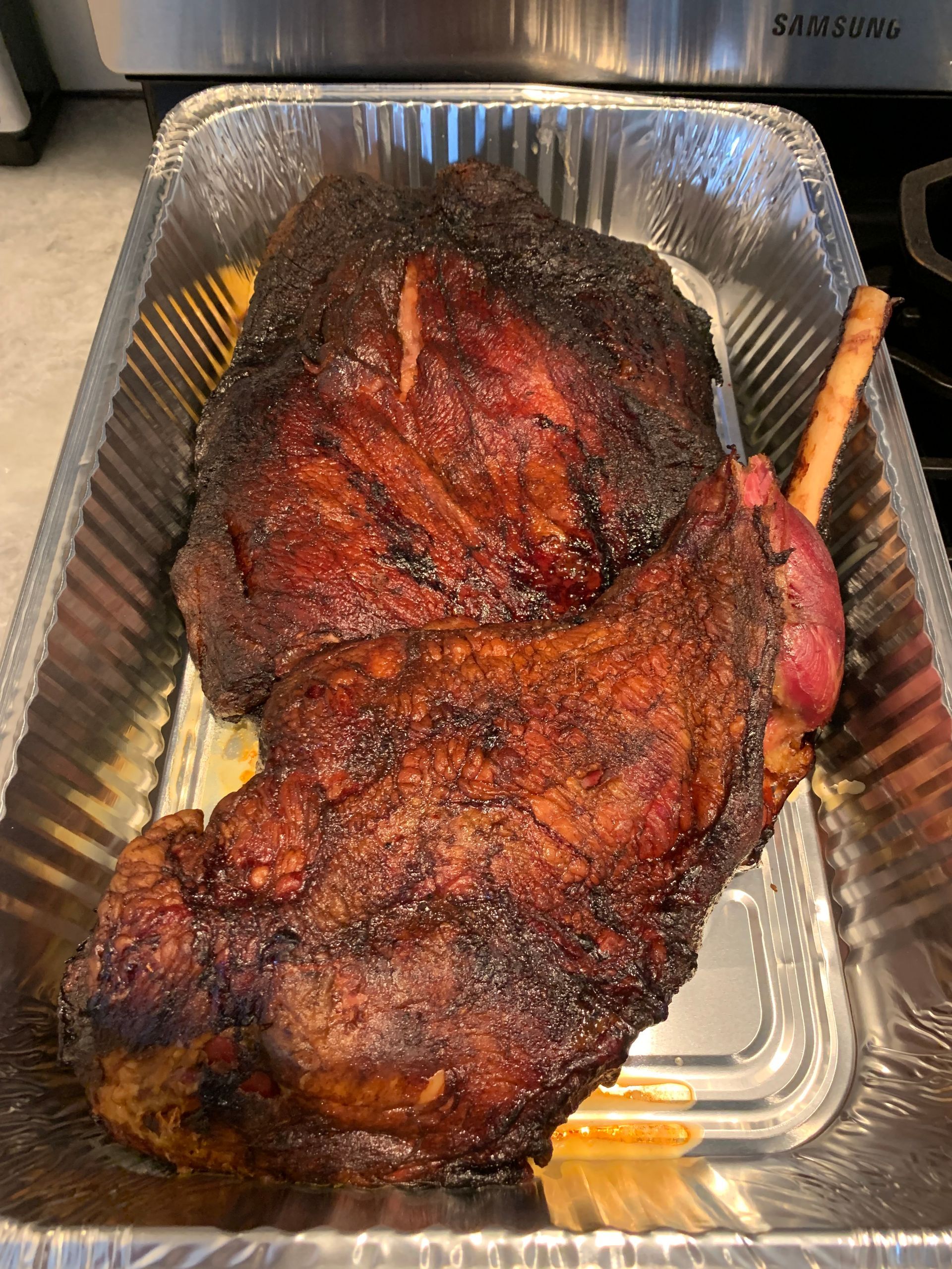 A large piece of meat is sitting in a tin foil pan.