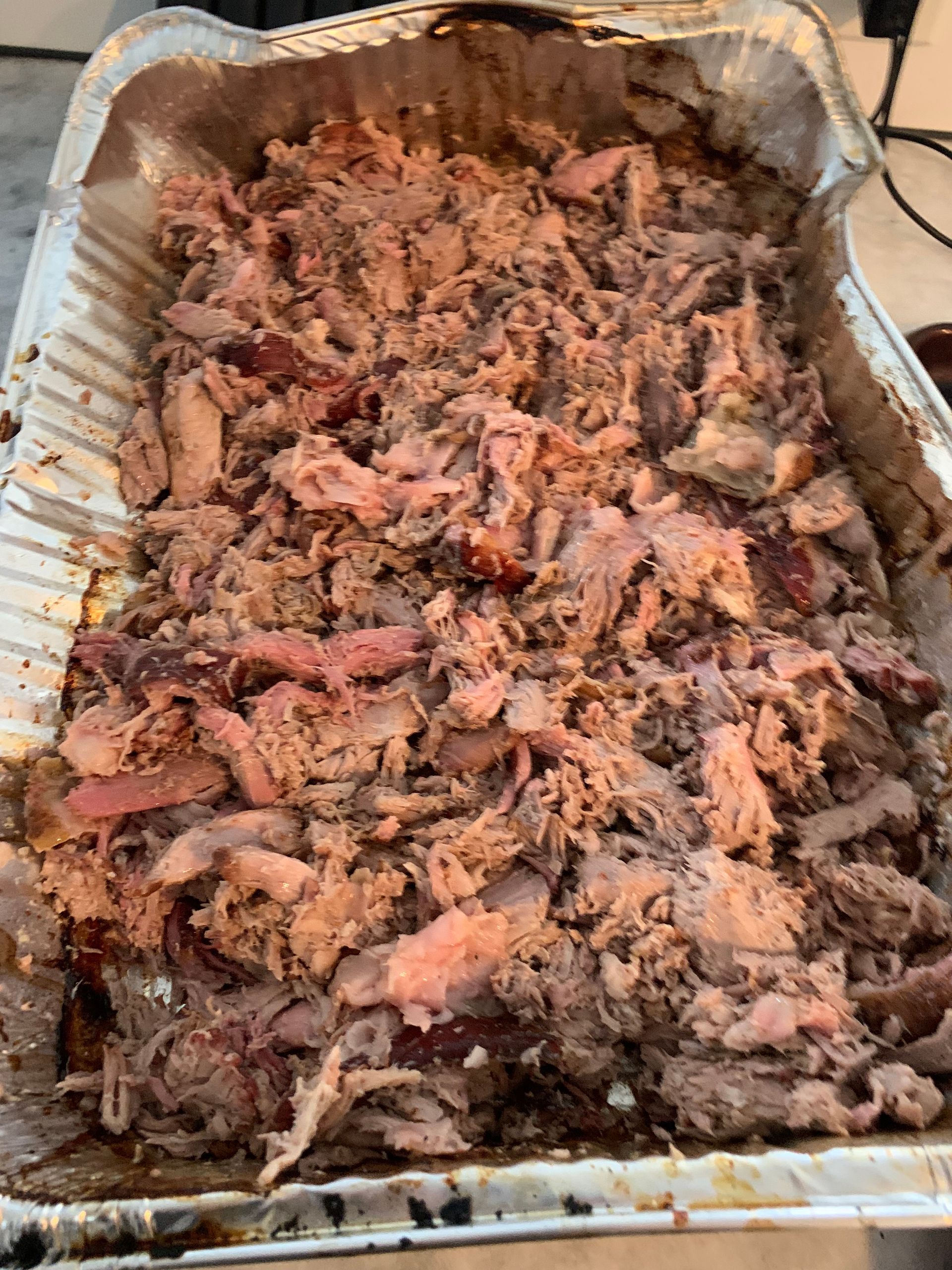 A tray of shredded pork is sitting on a table.