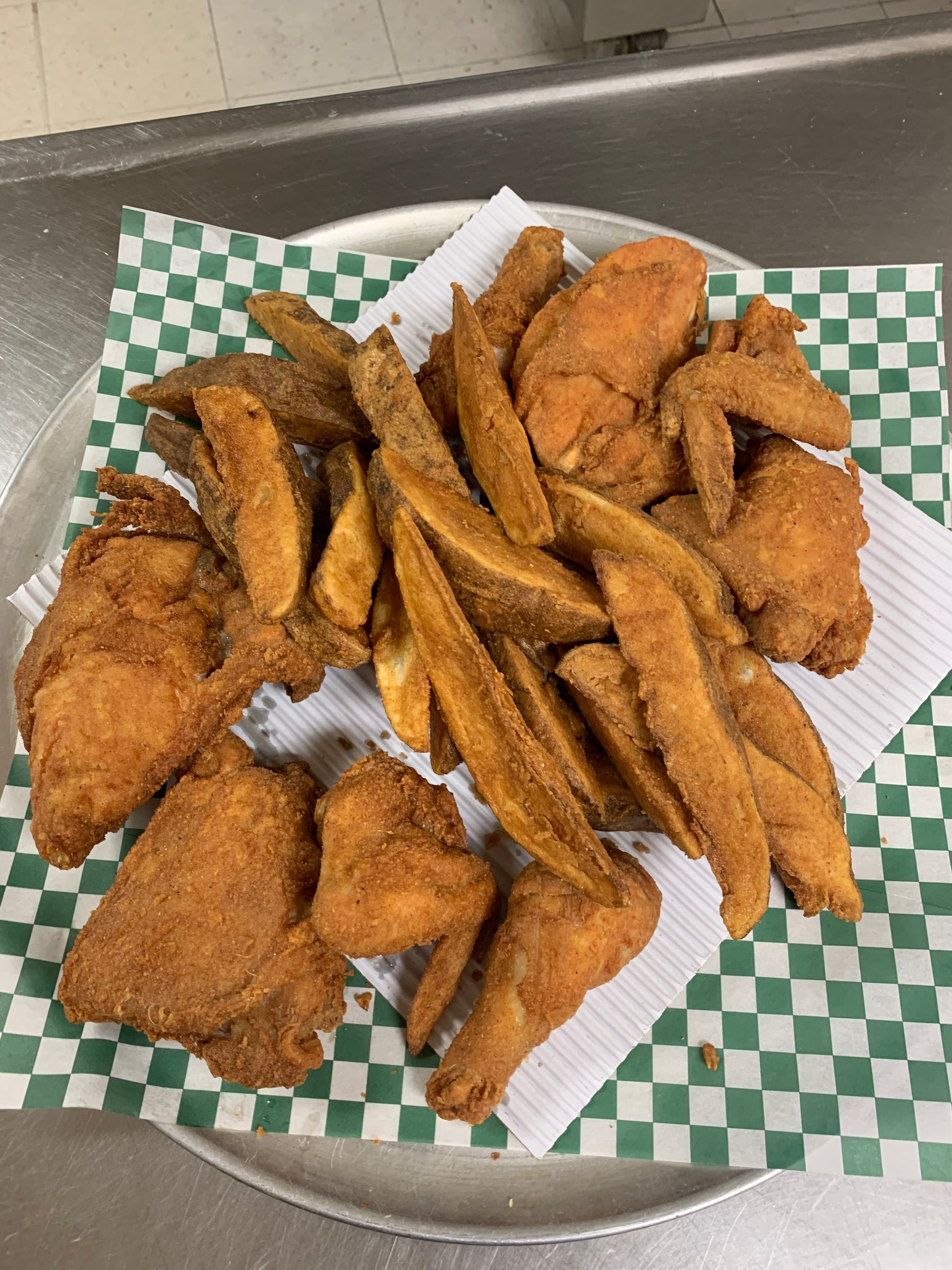 A plate of fried chicken and french fries on a checkered napkin.