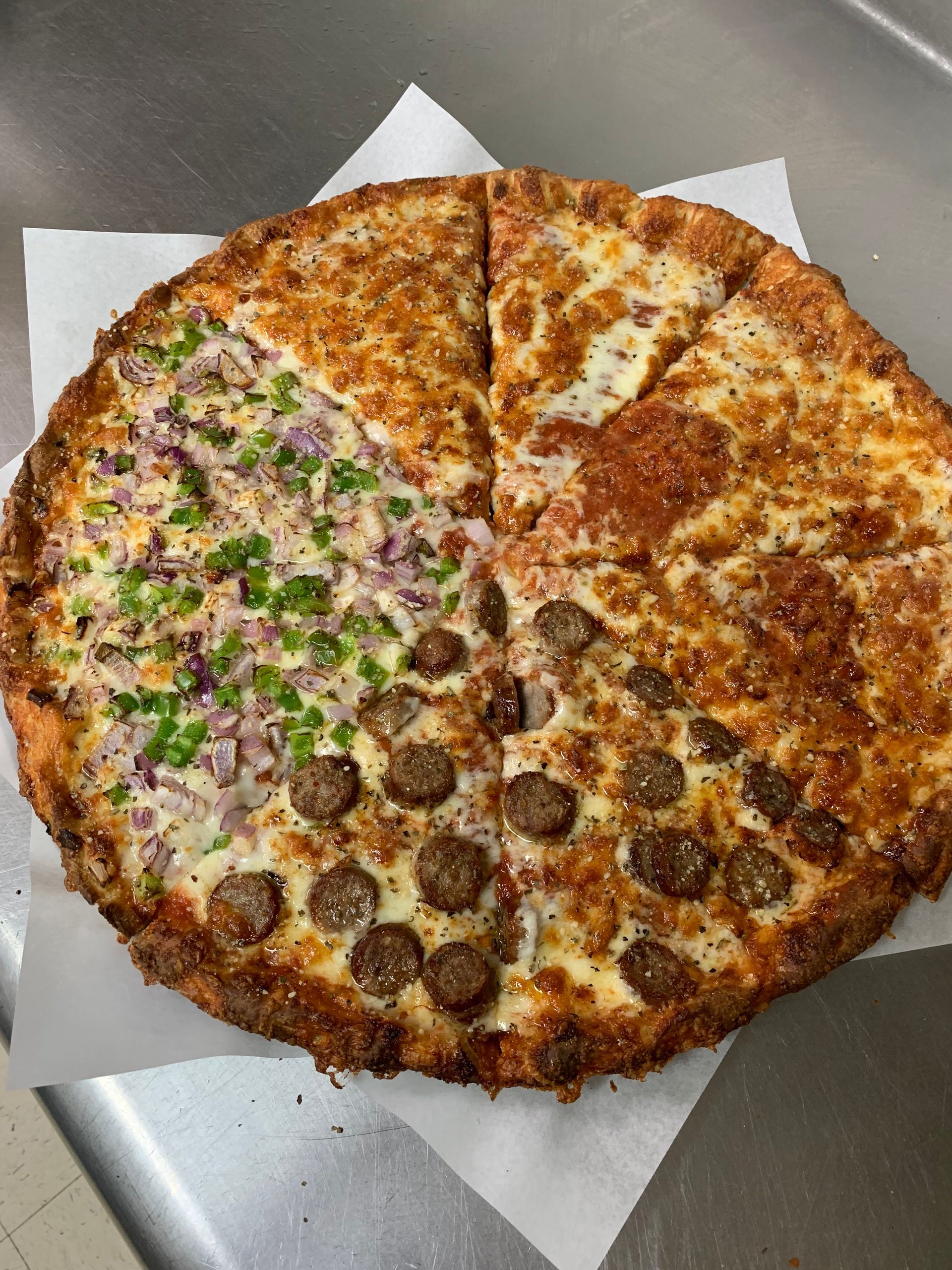 A pizza with four different toppings is sitting on a table.