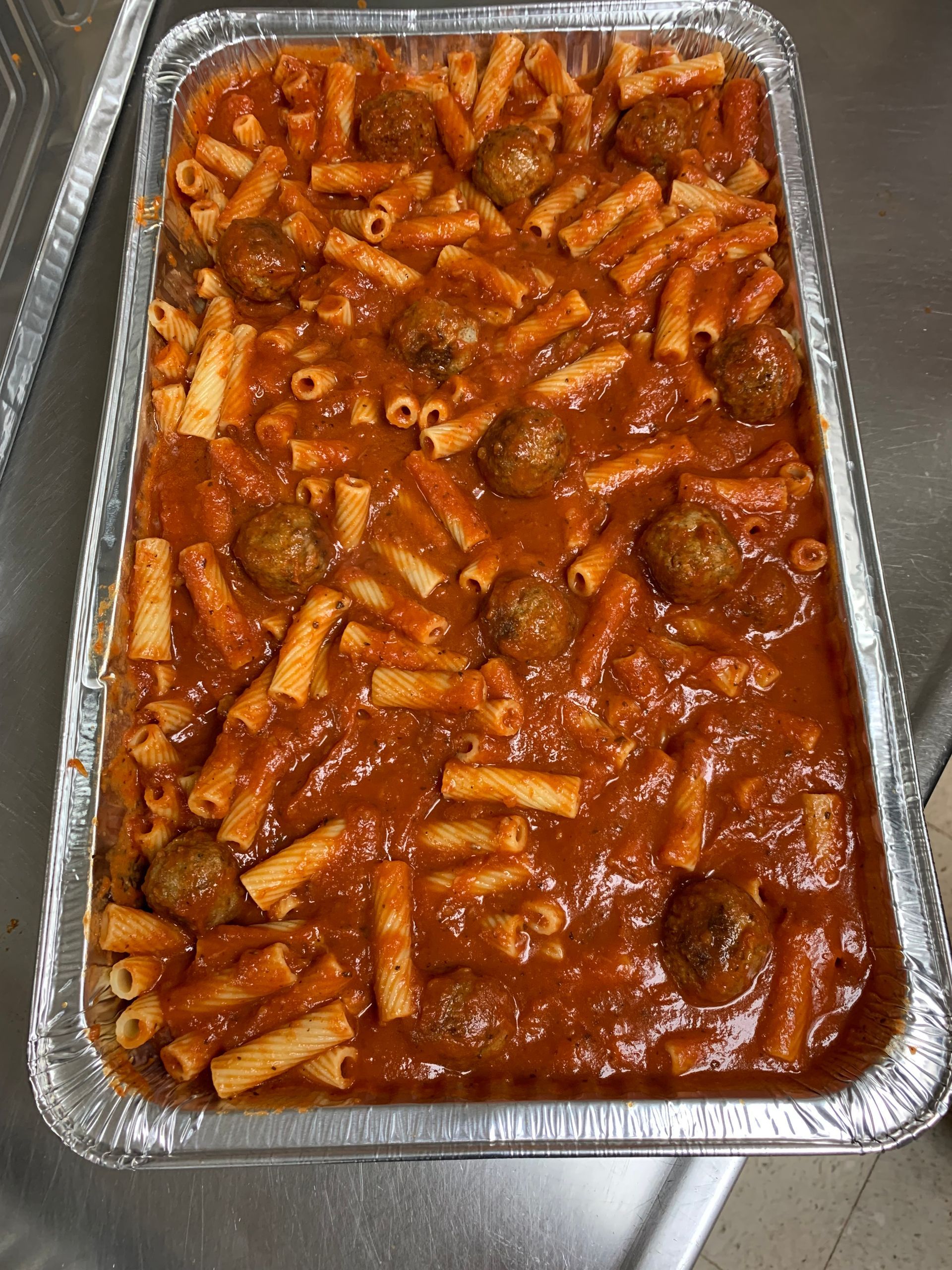 A casserole dish filled with pasta and meatballs in tomato sauce.