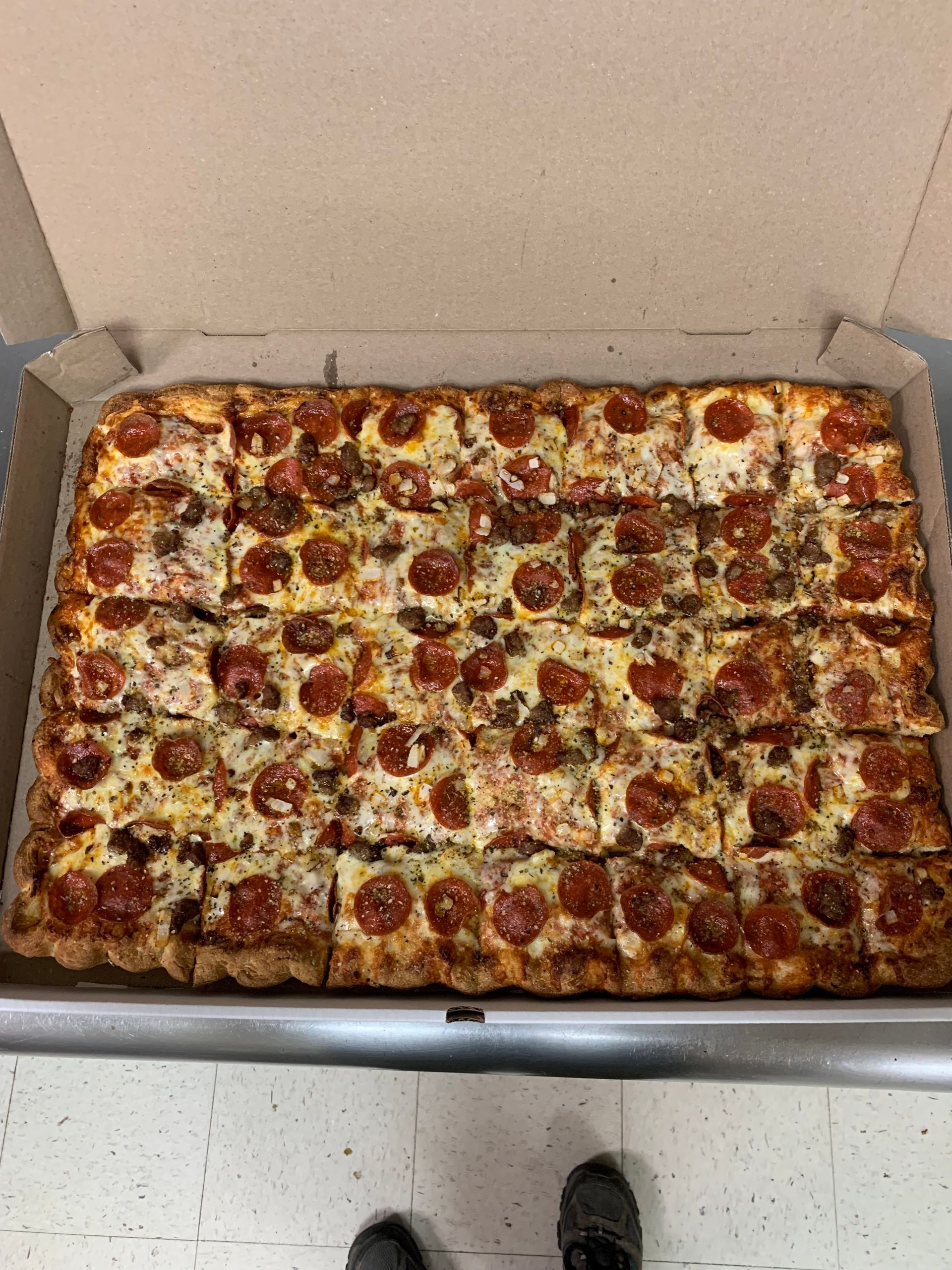 A large pepperoni pizza is in a cardboard box.