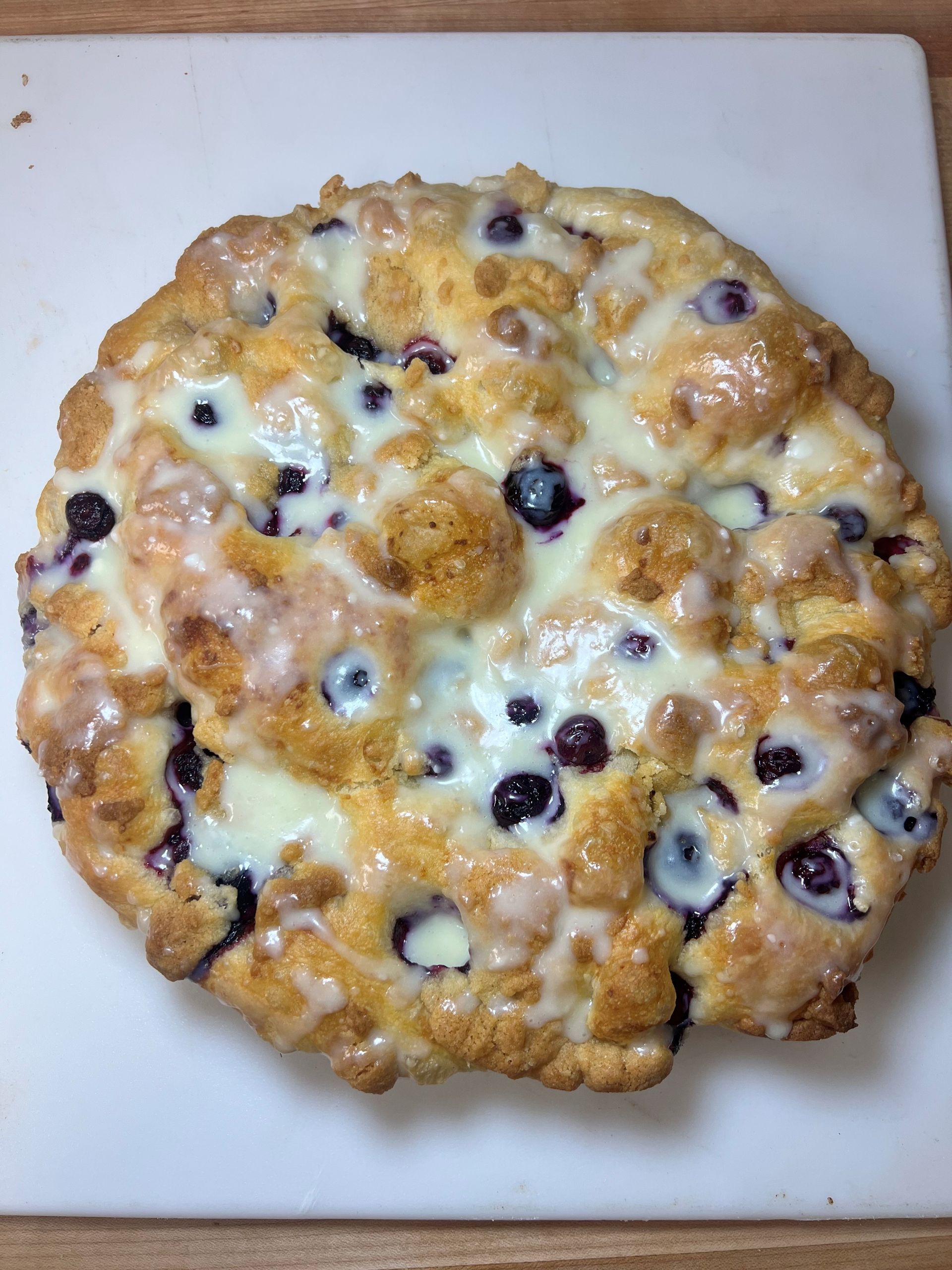 A pie with blueberries and white frosting on a cutting board
