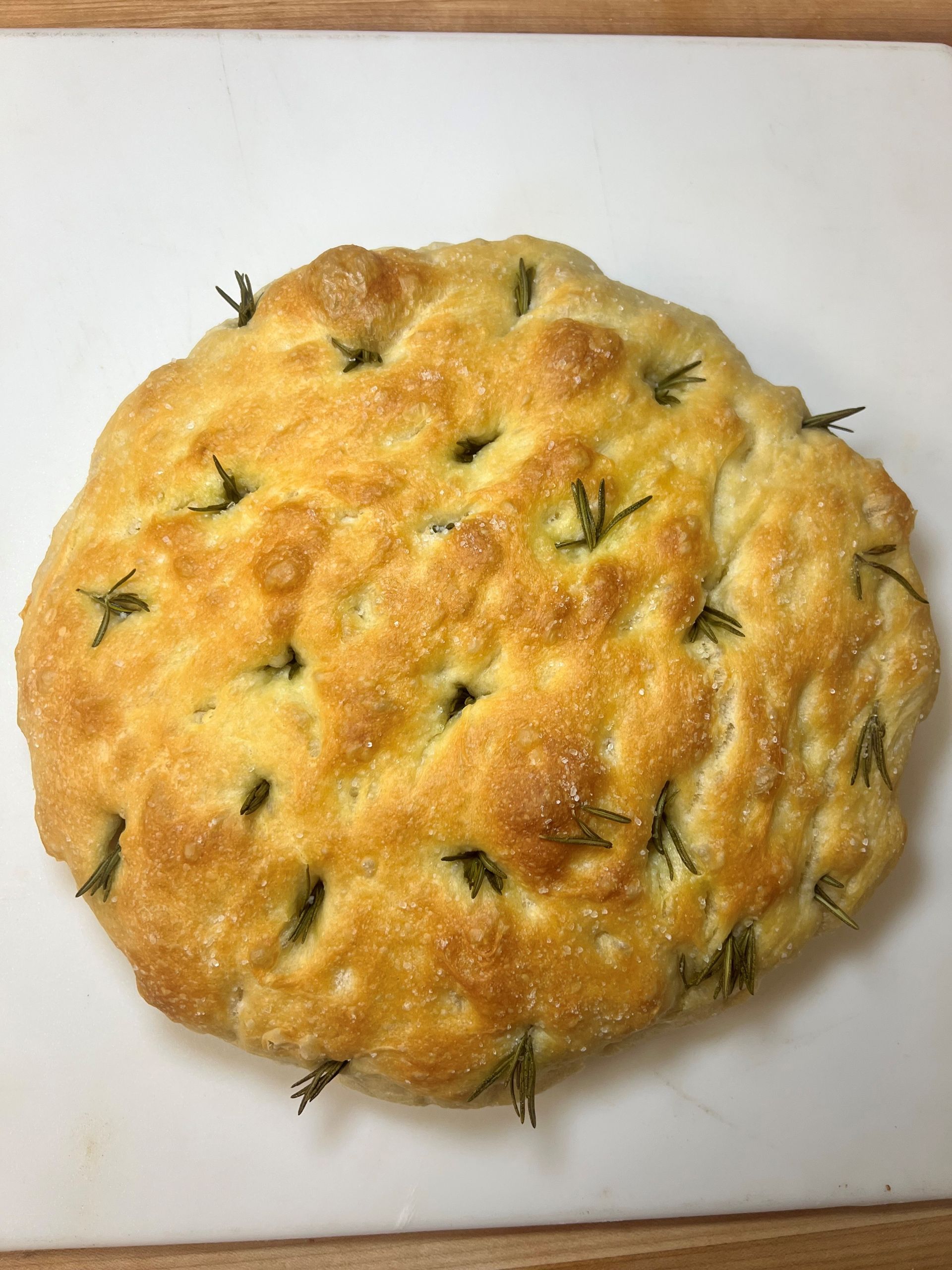 A loaf of bread is sitting on a white cutting board.