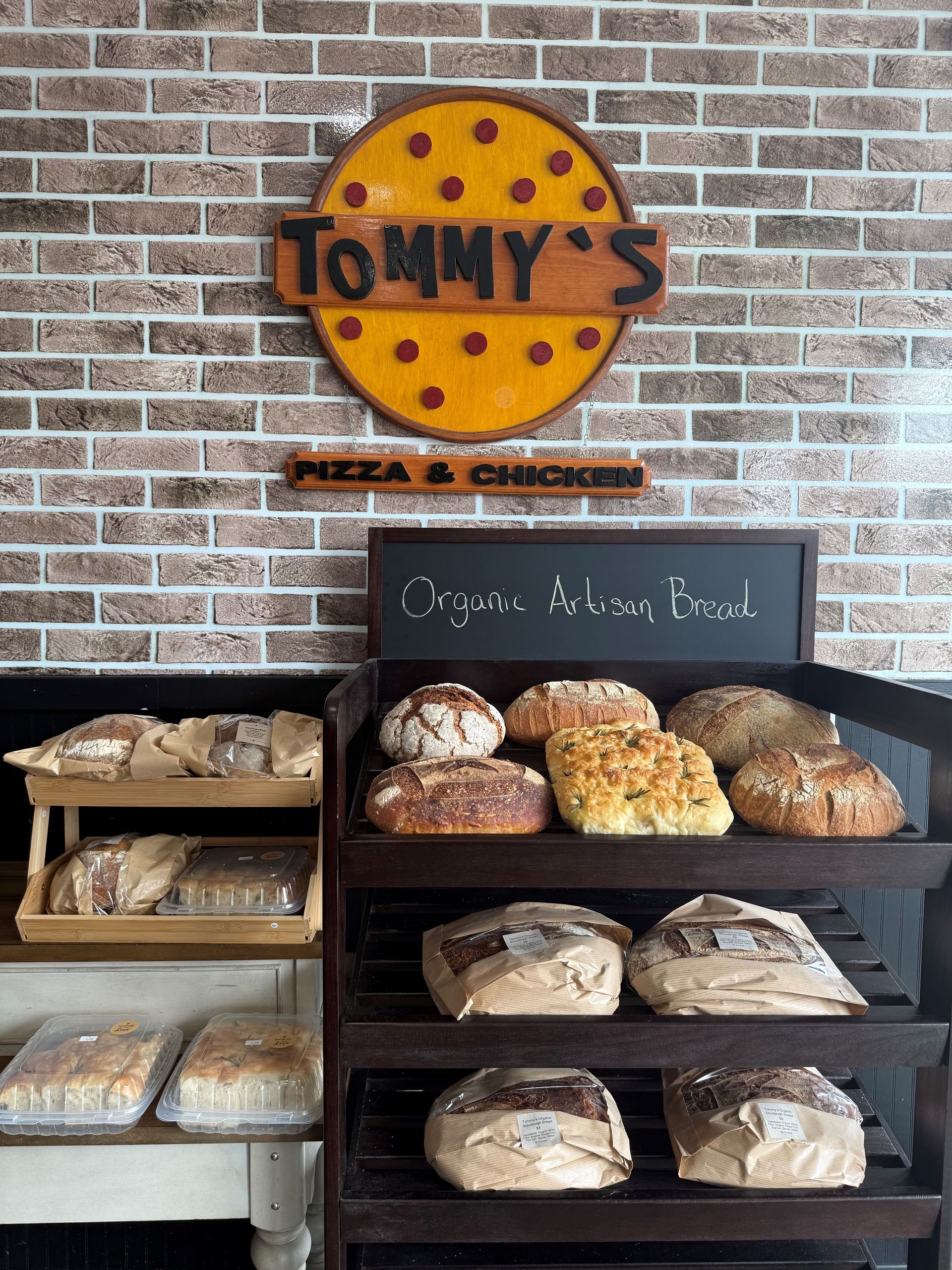 A bakery with lots of bread on display in front of a brick wall.
