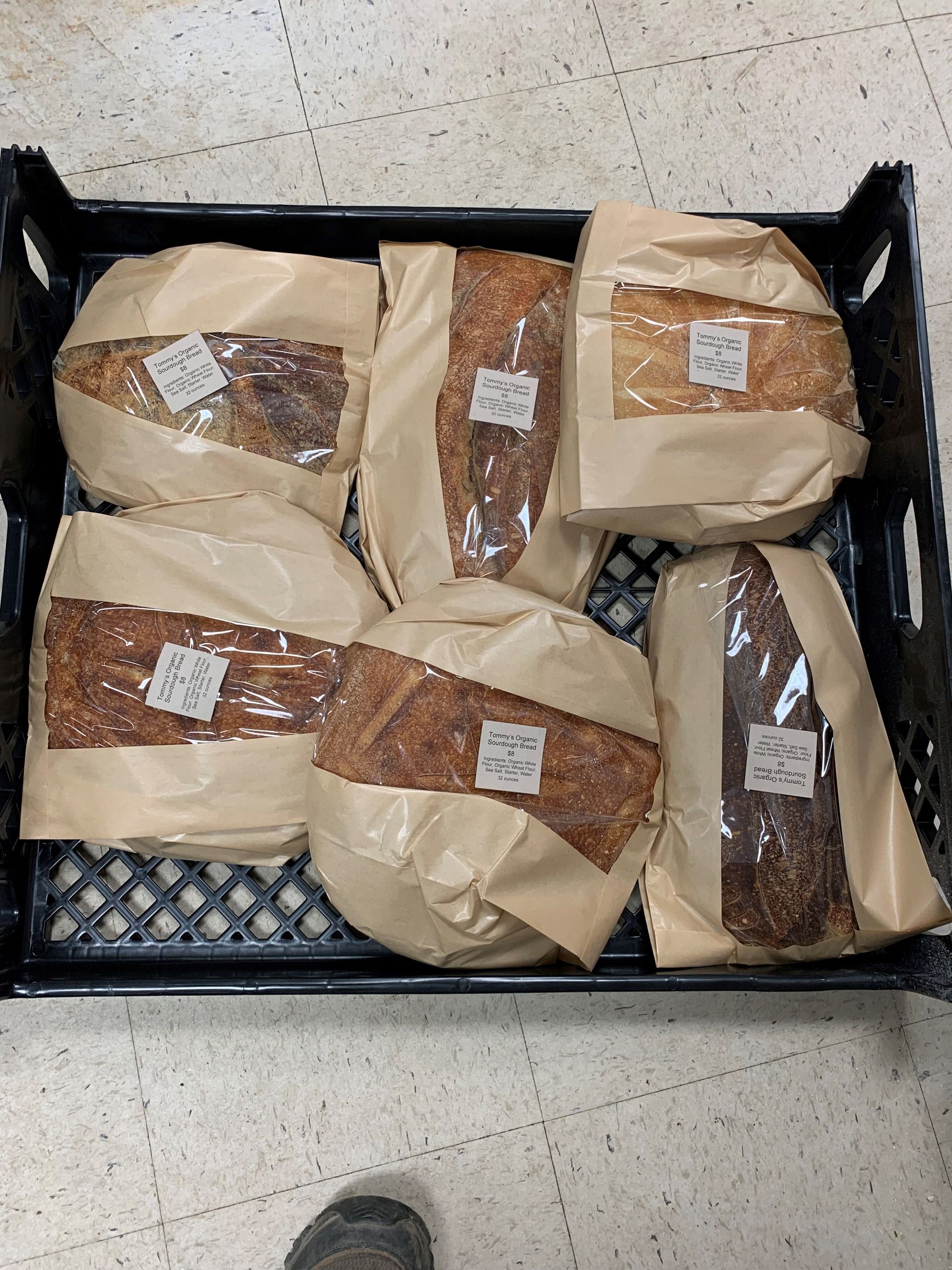 A black crate filled with bread wrapped in brown paper