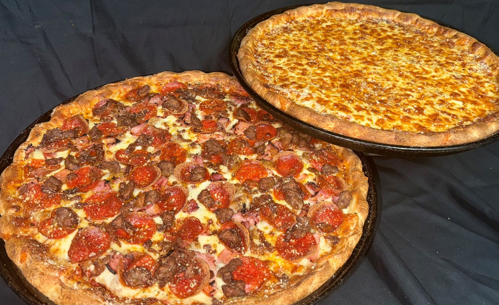 Two pizzas, one pepperoni and one cheese, are sitting on a table.